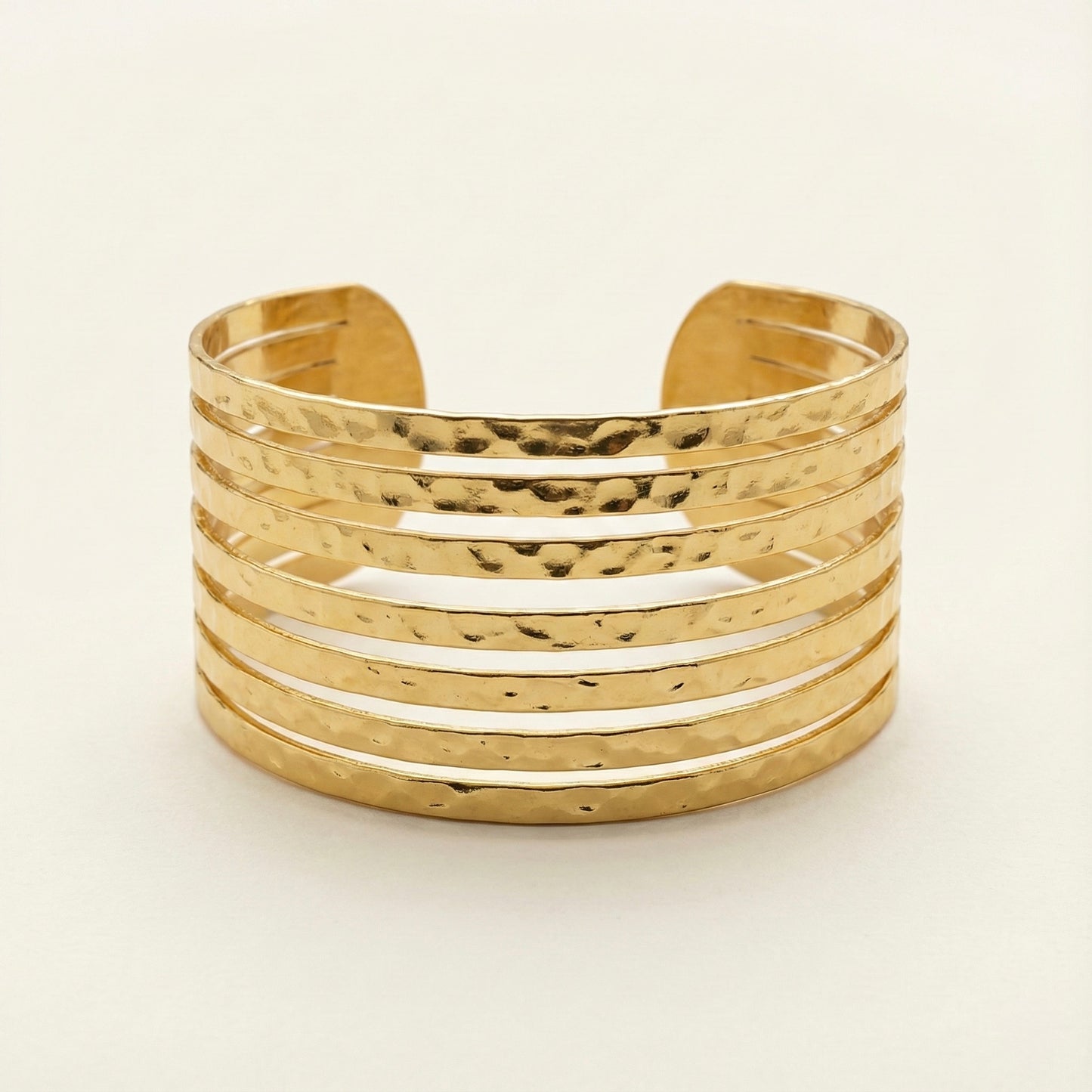 Gold cuff bracelet on a light beige background