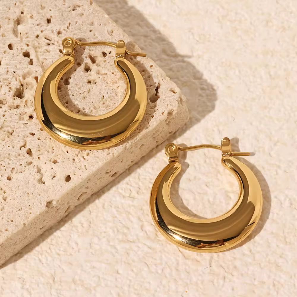 Gold hoop earrings on a textured beige surface