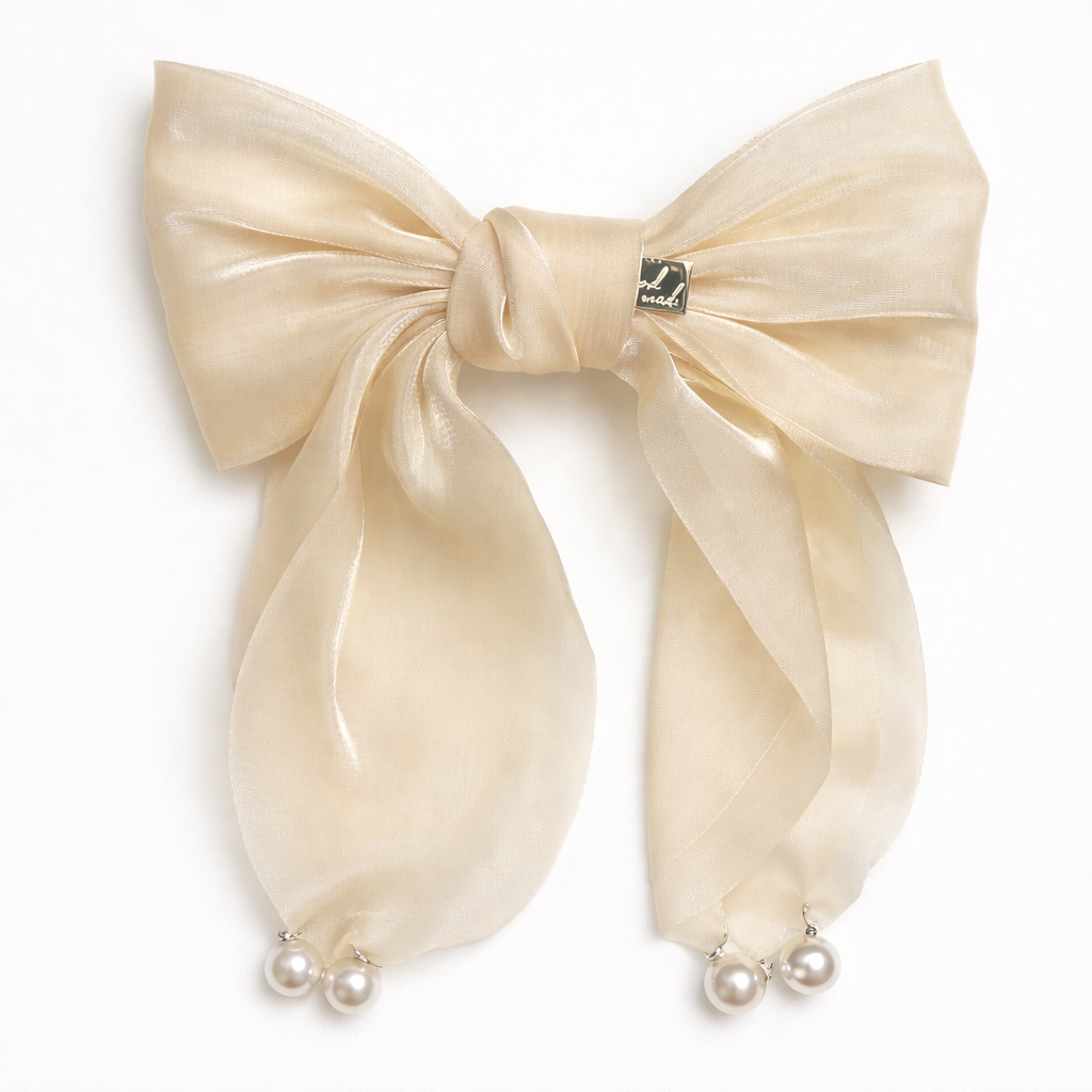 Large beige bow hair clip with pearl accents on a white background