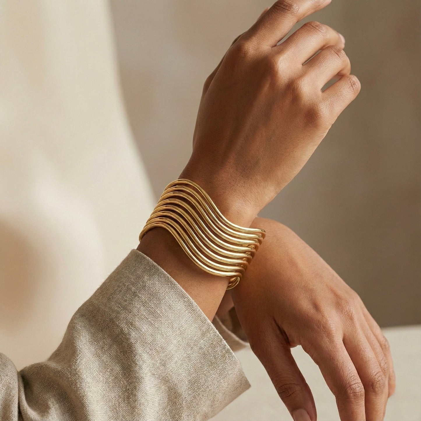 Gold bracelet on a wrist with a neutral background