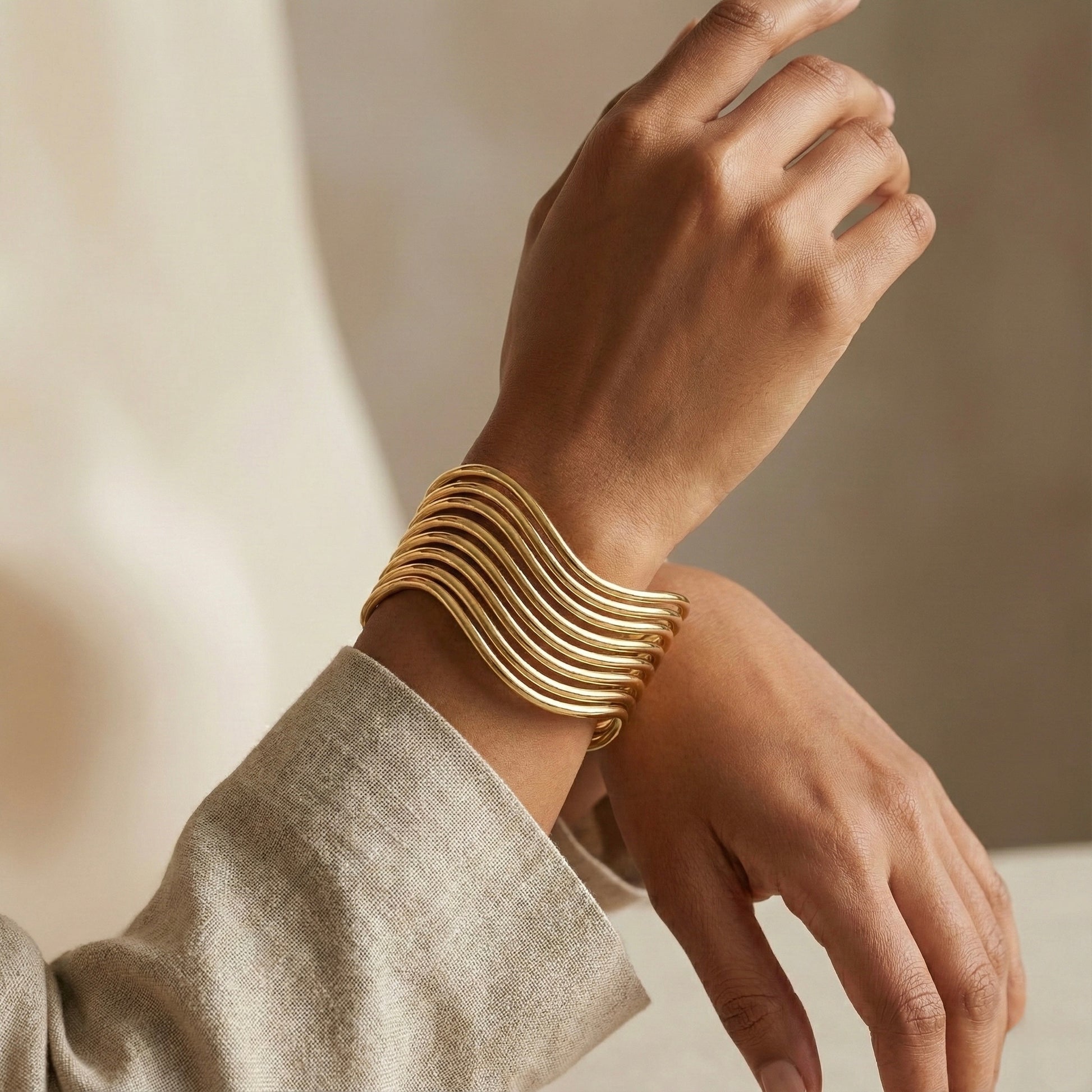 Gold bracelet on a wrist with a neutral background