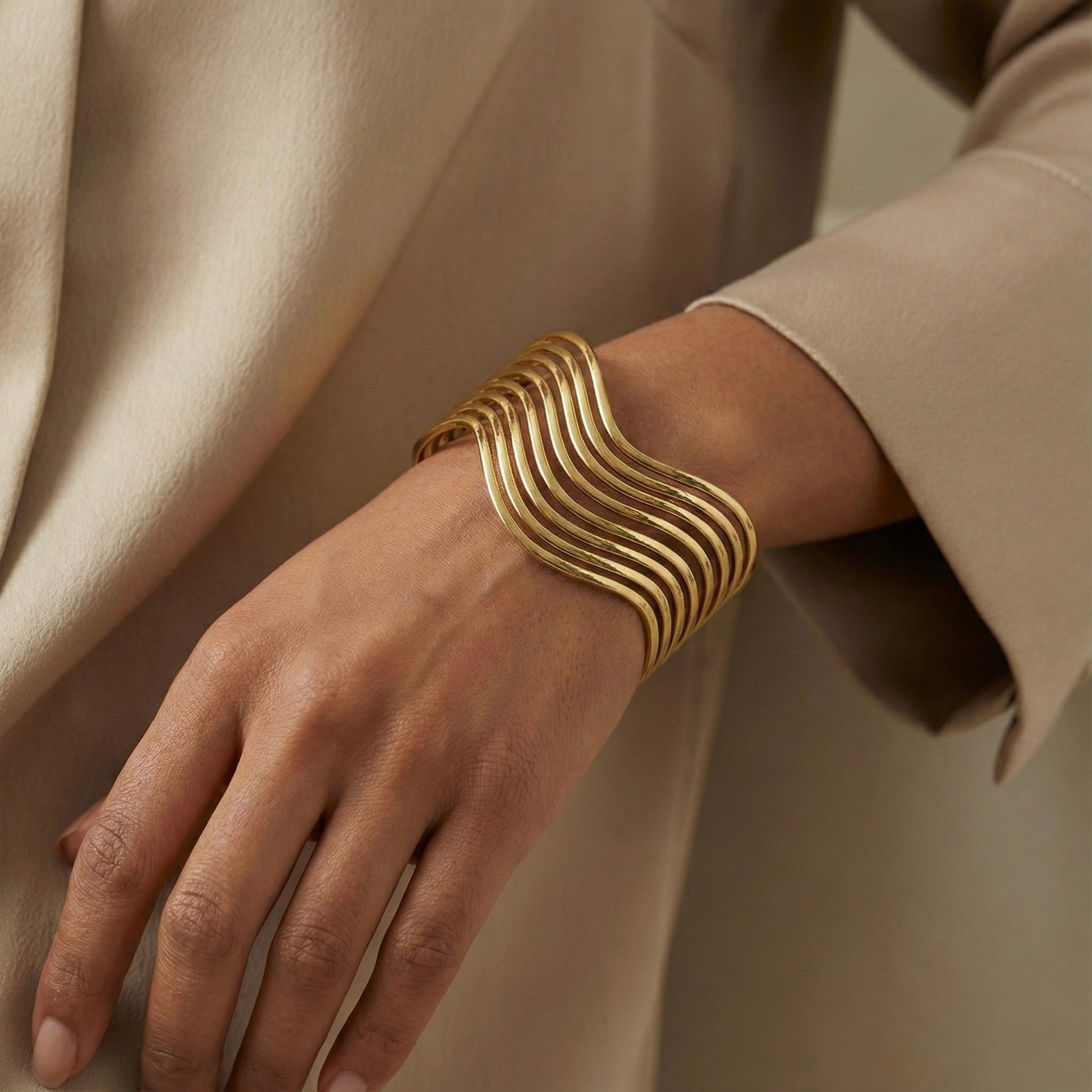 Gold bracelet on a wrist with a neutral background