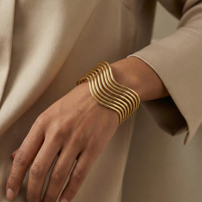Gold bracelet on a wrist with a neutral background