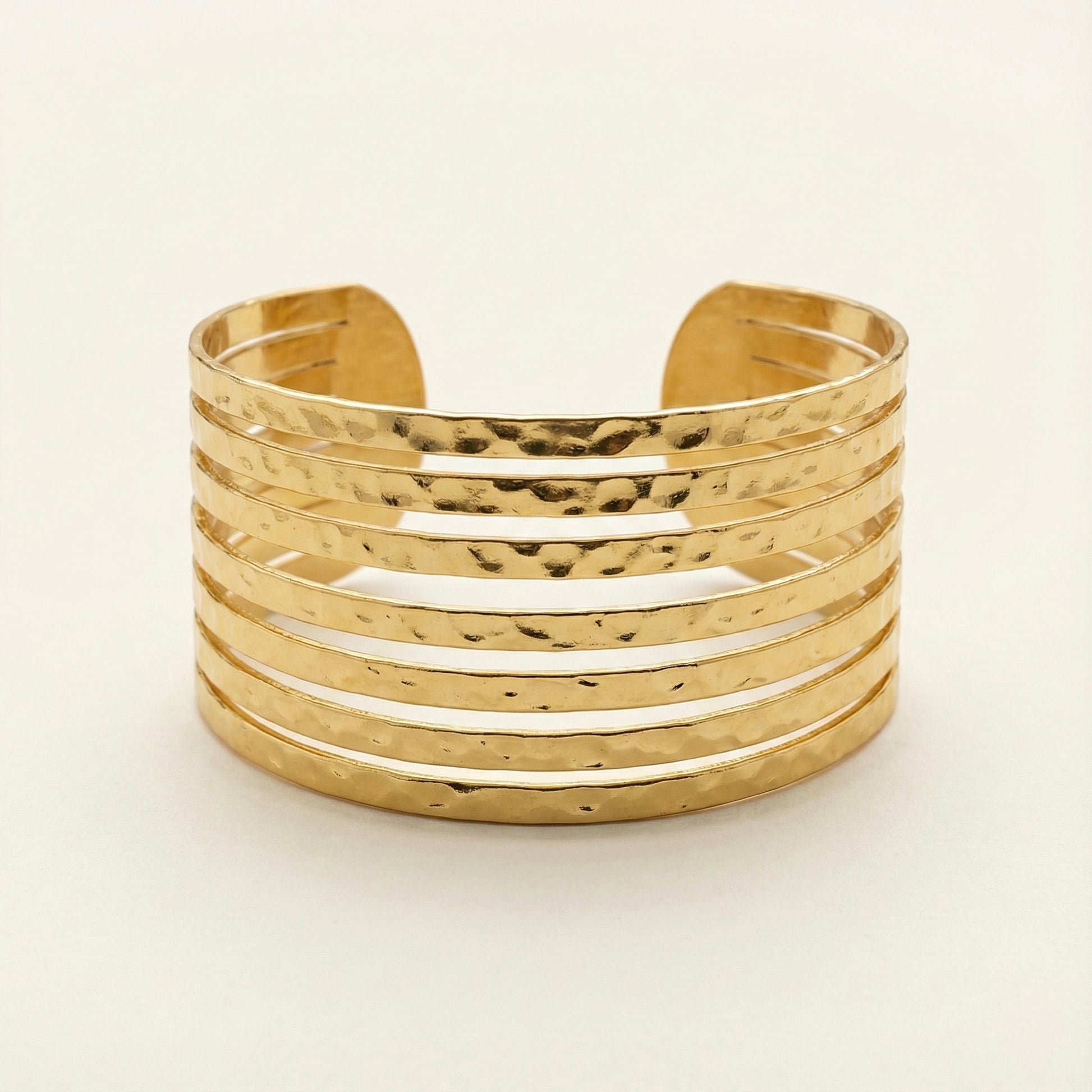 Gold cuff bracelet on a light beige background