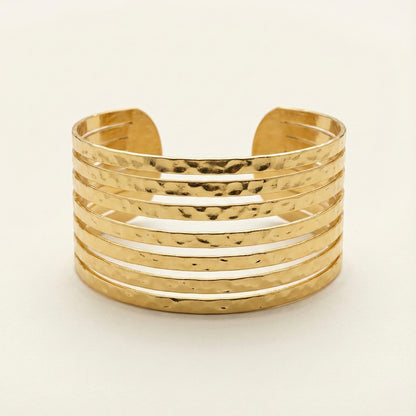 Gold cuff bracelet on a light beige background