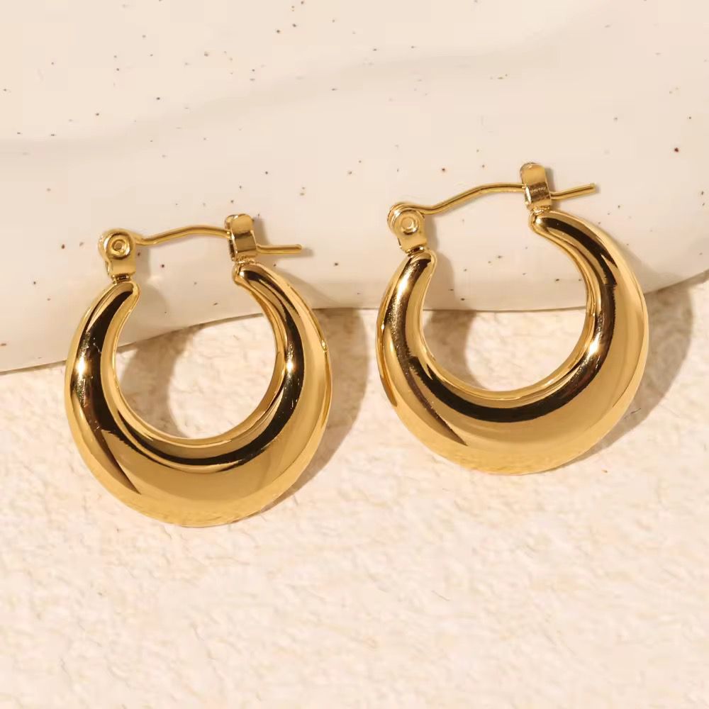 Pair of gold hoop earrings on a textured beige background