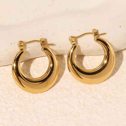 Pair of gold hoop earrings on a textured beige background