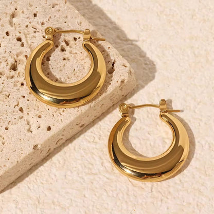Gold hoop earrings on a textured beige surface
