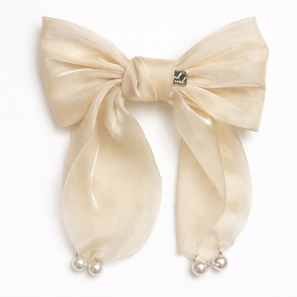 Large beige bow hair clip with pearl accents on a white background