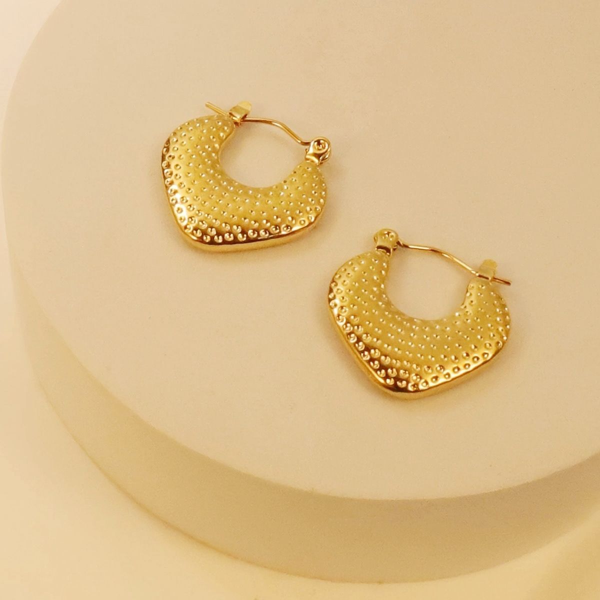 Gold hoop earrings on a beige background