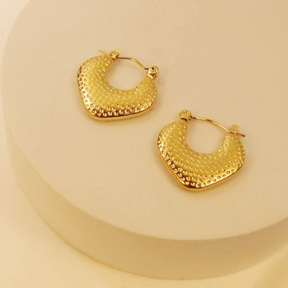 Gold hoop earrings on a beige background