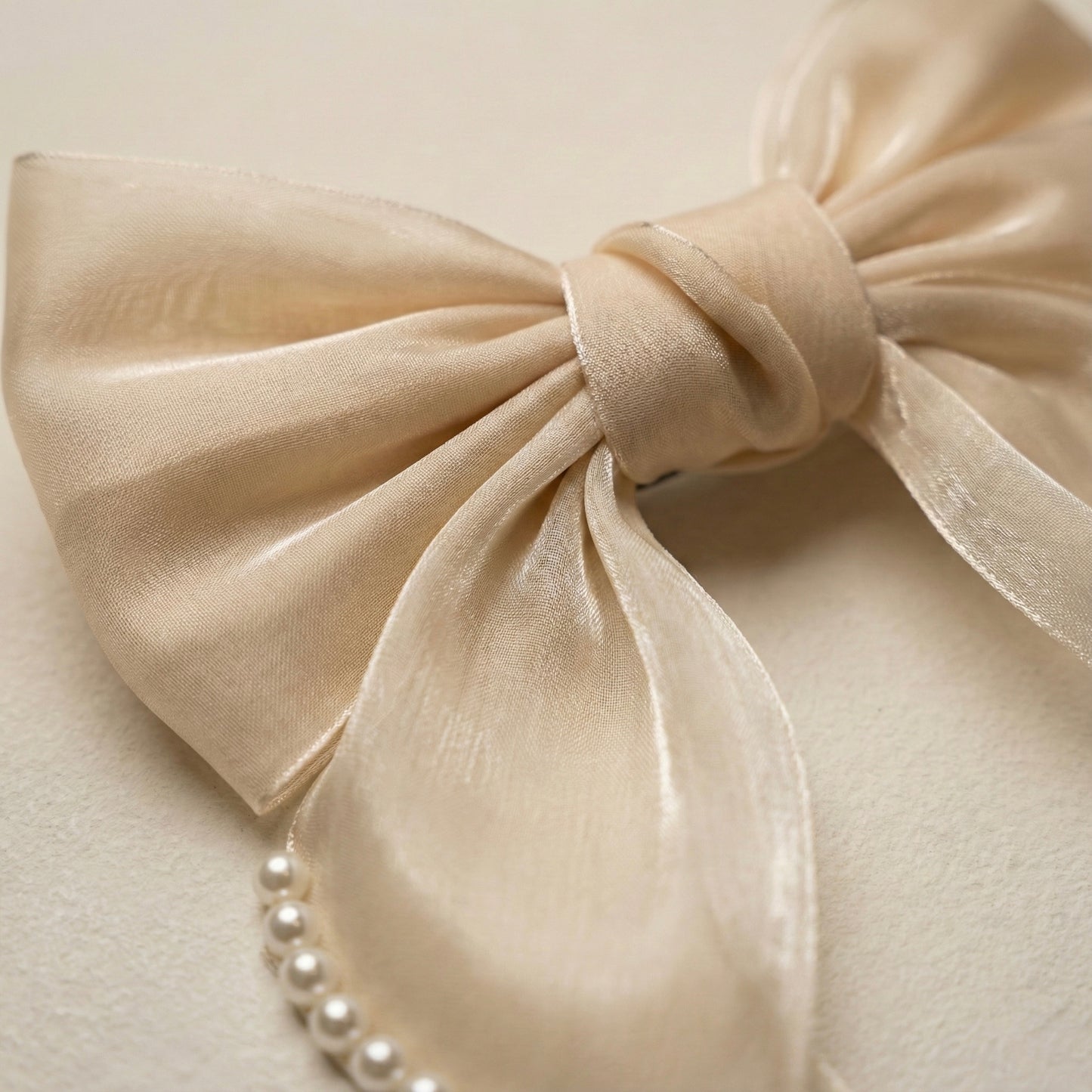 Close-up of a beige bow with pearls on a light background