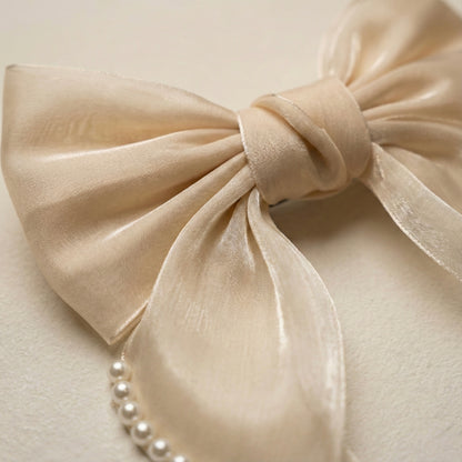 Close-up of a beige bow with pearls on a light background