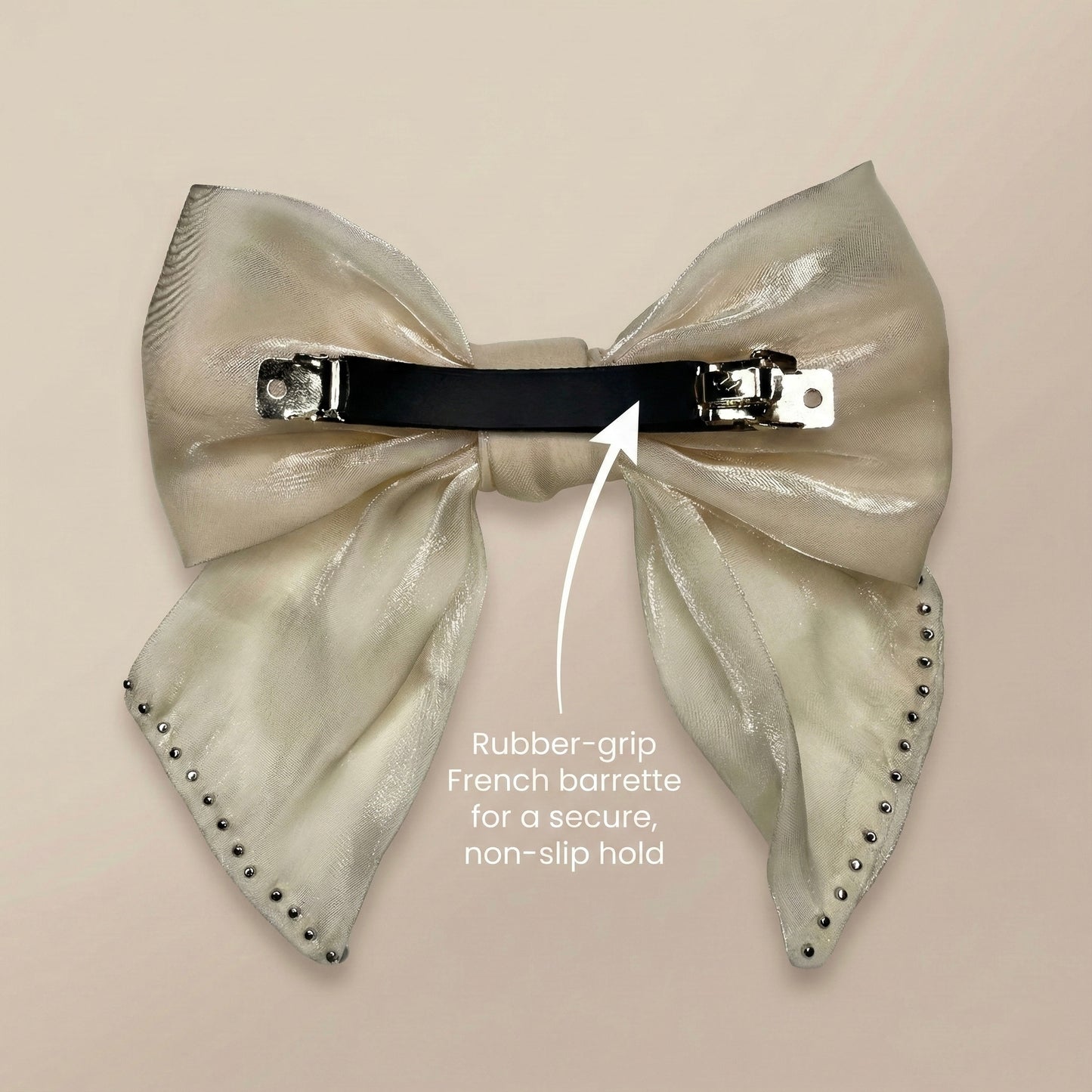 Large metallic bow hair clip with rubber-grip French barrette on a beige background