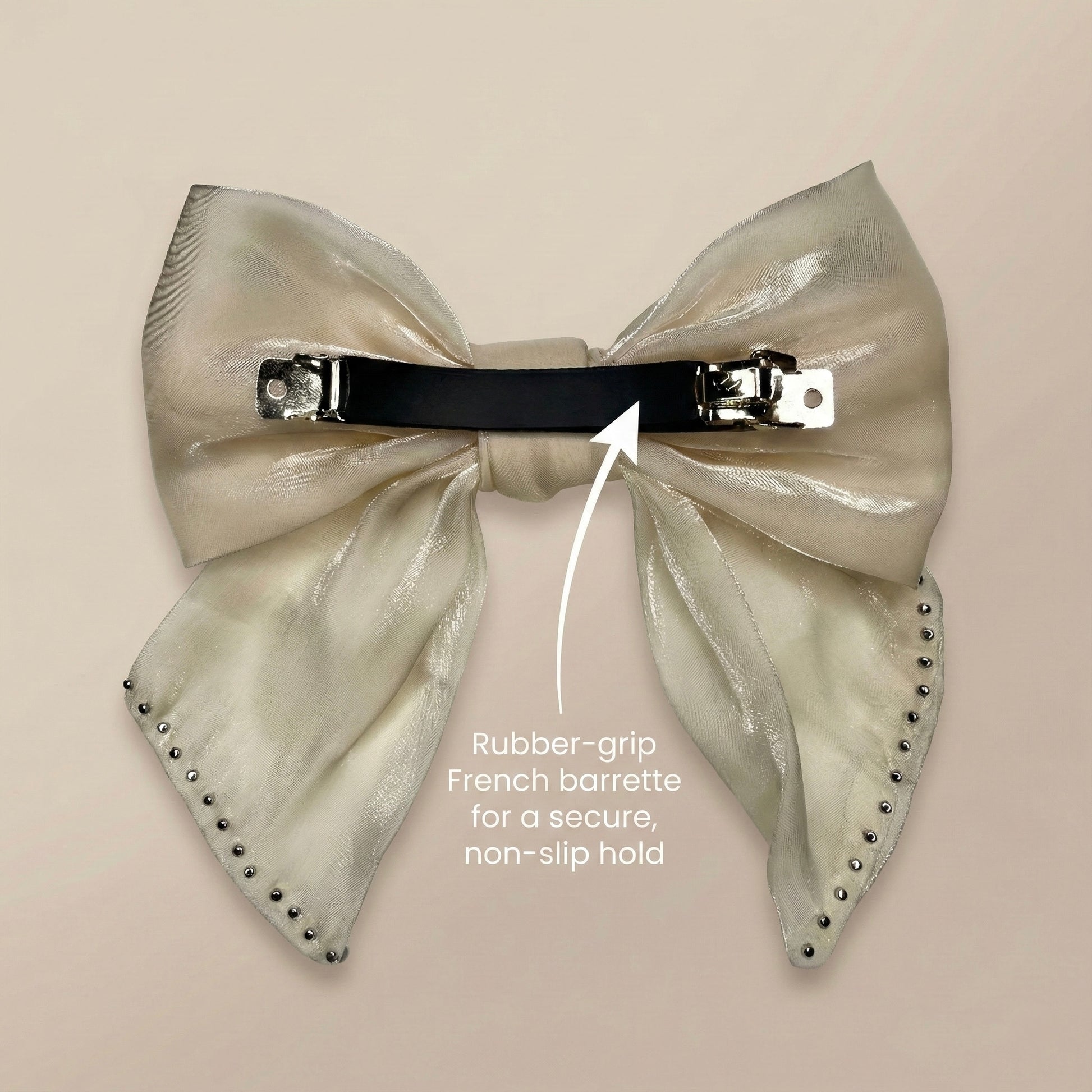 Large metallic bow hair clip with rubber-grip French barrette on a beige background