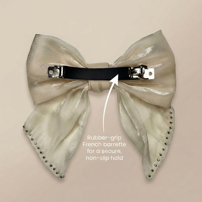 Large metallic bow hair clip with rubber-grip French barrette on a beige background