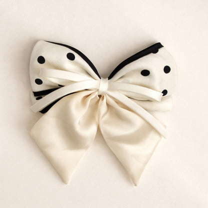 White bow with black polka dots on a light beige background