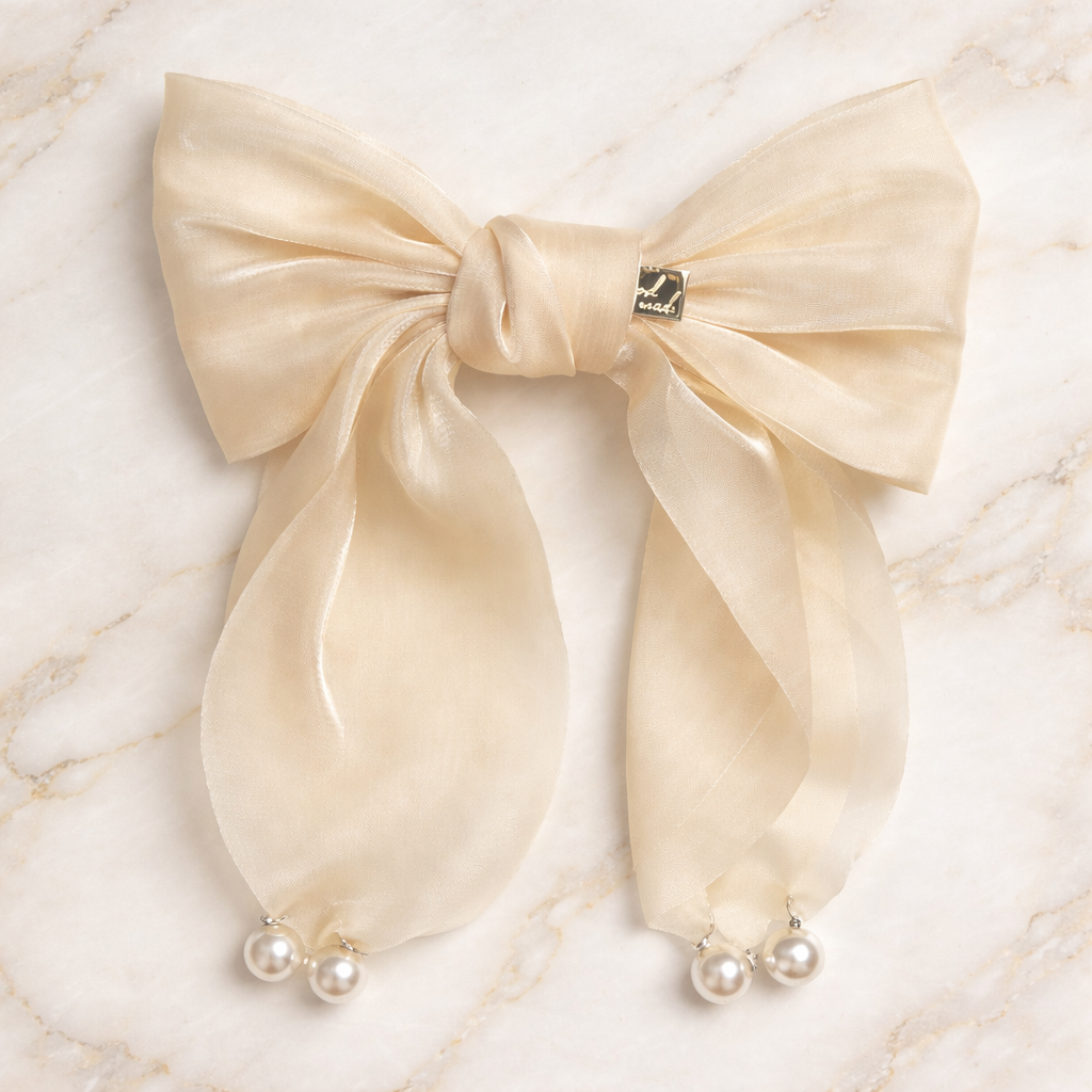 Cream-colored bow with pearl decorations on a marble background